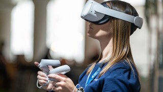 Junge Frau mit VR-Brille vom Meta-Konzern und zwei Touch-Controllern in den Händen