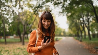 Frau im Park schaut aufs iPhone.