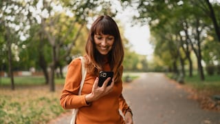 Frau im Park schaut aufs iPhone.