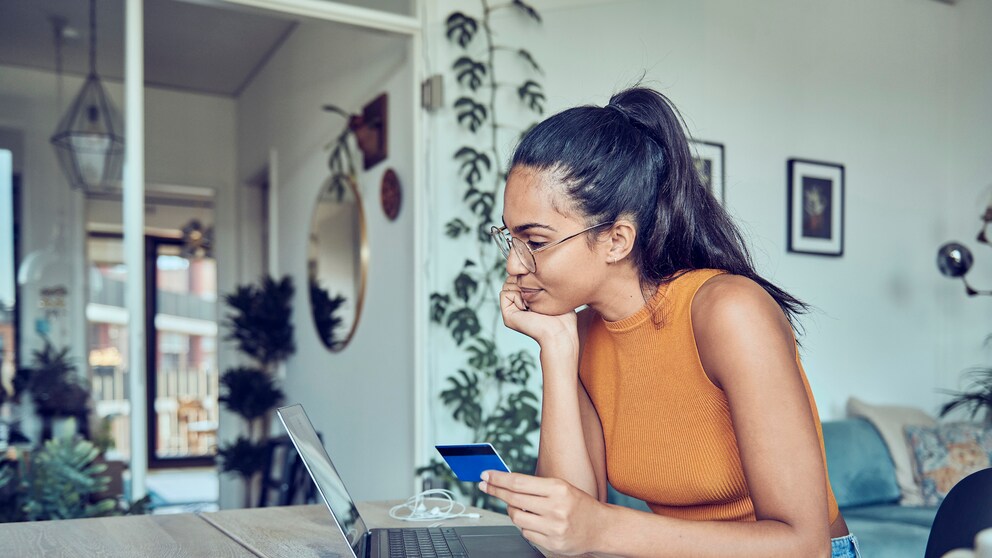 Junge Frau am Laptop mit einer Girokarte probiert neue Funktionen für den Online-Handel aus.