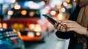 Frau mit Smartphone auf dunkler Straße