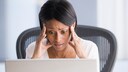 Frau sitzt am Laptop und fällt auf Job-Betrug auf Ebay Kleinanzeigen rein: 2 Arten, die Nutzer kennen sollten