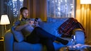 Mann nutzt Smartphone beim Fernsehen
