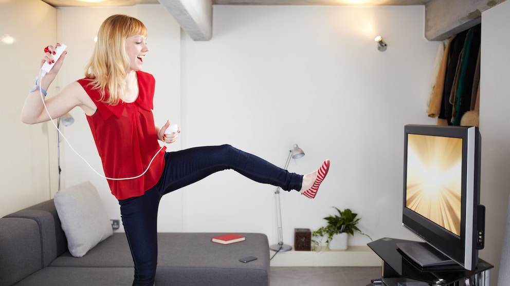 Sport Games Symbolbild: Frau mit Controller vor Fernseher