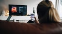 Streaming illegal kostenlos Symbolbild: Frau mit Handy schaut Fernsehen