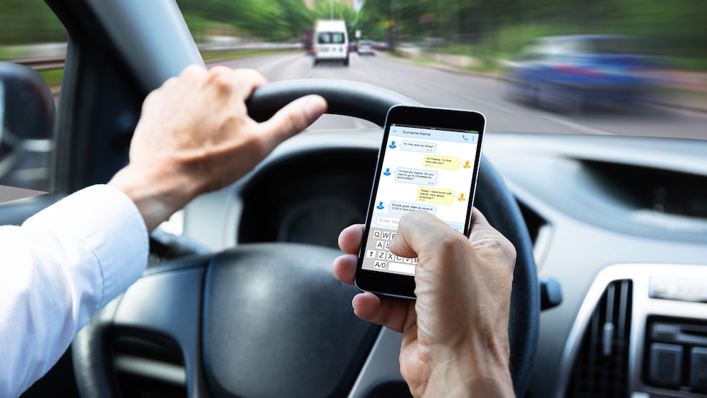Handy am Steuer, Mann schreibt Textnachrichten beim Autofahren