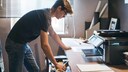 Mann steht vor einem Drucker