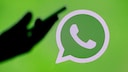 WhatsApp Logo dunkle Hand: unbekannte Anrufe blockieren Symbolbild