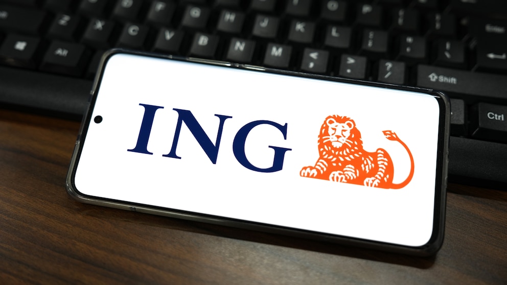 ING App Update Symbolbild: ING-Logo auf Smartphone, das auf Laptop-Tastatur liegt
