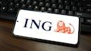 ING App Update Symbolbild: ING-Logo auf Smartphone, das auf Laptop-Tastatur liegt