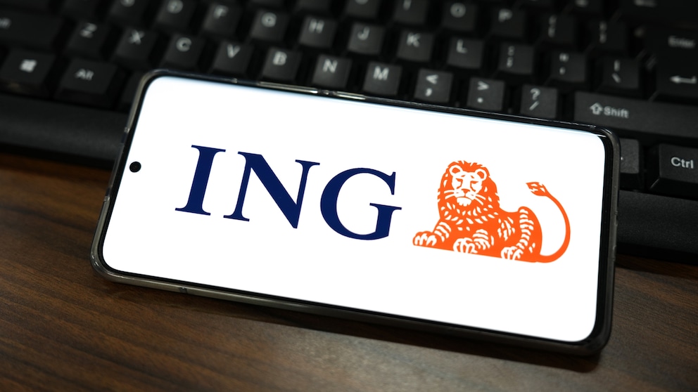 ING App Update Symbolbild: ING-Logo auf Smartphone, das auf Laptop-Tastatur liegt