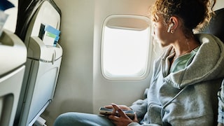Mädchen mit Bluetooth-Kopfhörern im Flugzeug