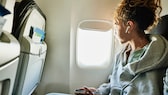 Mädchen mit Bluetooth-Kopfhörern im Flugzeug