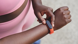 Frau trägt einen orange-farbenen Fitnesstracker