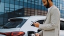 Mann mit Smartphone in der Hand tankt ein Elektroauto