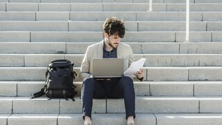 Mann sitzt mit Laptop auf Treppe