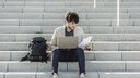 Mann sitzt mit Laptop auf Treppe