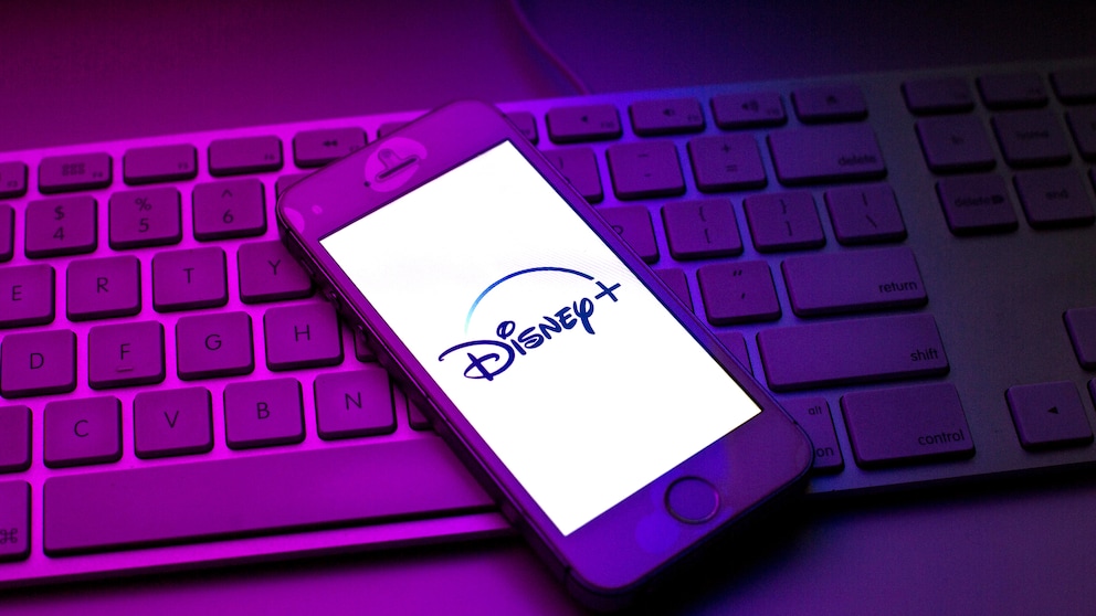 Disney+ streicht Filme und serien Symbolbild: Disney+-Logo auf Smartphone, das auf einer Tastatur liegt