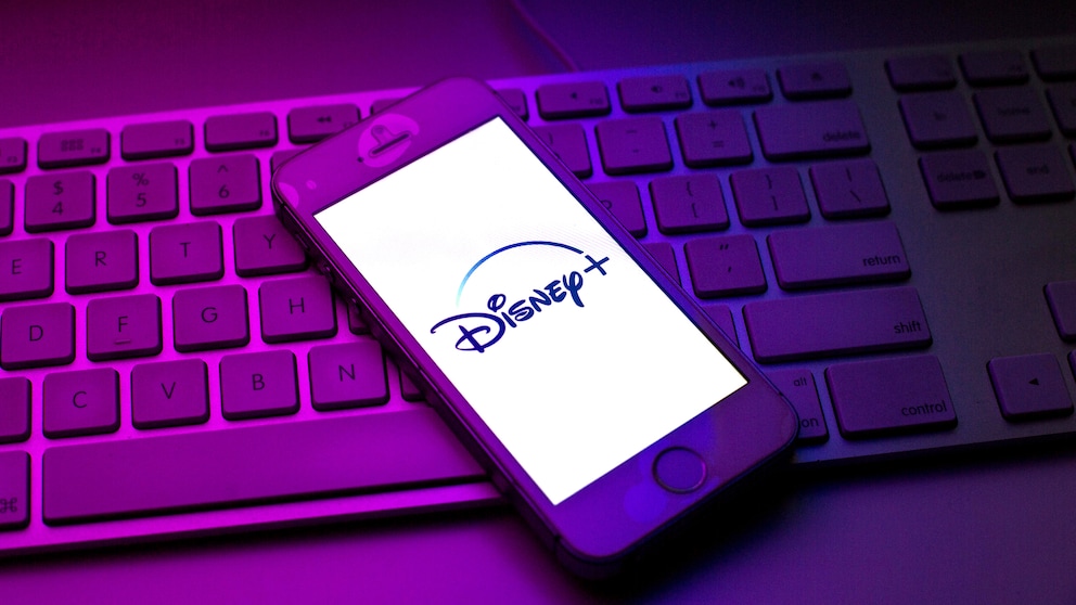 Disney+ streicht Filme und serien Symbolbild: Disney+-Logo auf Smartphone, das auf einer Tastatur liegt