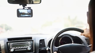 Person fährt Auto und neben dem Spiegel hängt eine Dashcam.