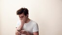 Smishing Symbolbild: entsetzter junger Mann mit Smartphone