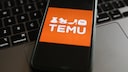Online-Shop Temu: Logo auf Smartphone, das auf einer Tastatur liegt