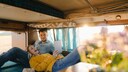 Glückliches Paar in Camping-Van schaut auf Tablet