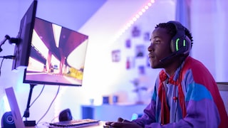 Mann sitzt vor Gaming-Monitoren und zockt