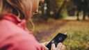 Frau im Park checkt ihre Selftracking App auf dem Smartphone
