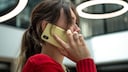 Junge Frau mit rotem Pulli telefoniert mit dem Smartphone.