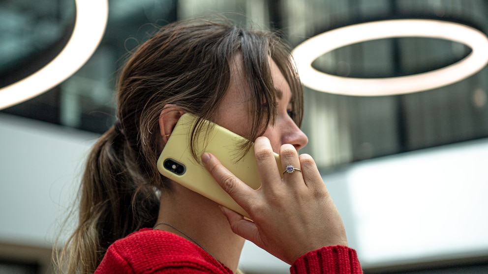 Junge Frau mit rotem Pulli telefoniert mit dem Smartphone.