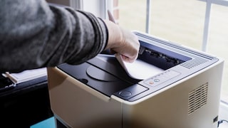 Jemand legt Papier in einen Laserdrucker