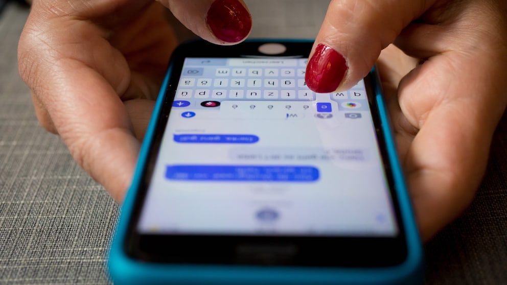 Frauenhand tippt eine iMessage auf einem iPhone.