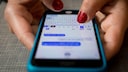 Frauenhand tippt eine iMessage auf einem iPhone.