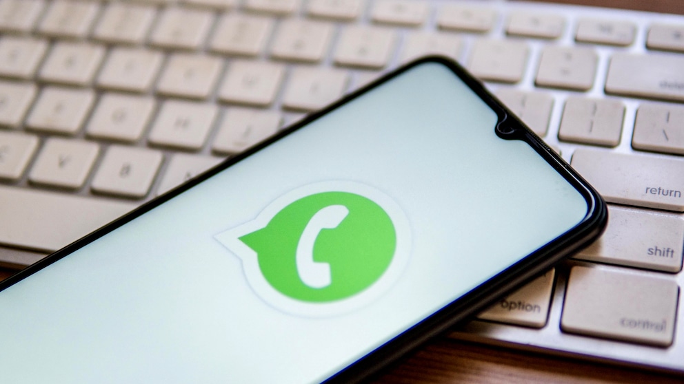 WhatsApp Datenschutzrichlinien: Grünes Logo des Messengers auf einem Smartphone, das auf einer Tastatur liegt
