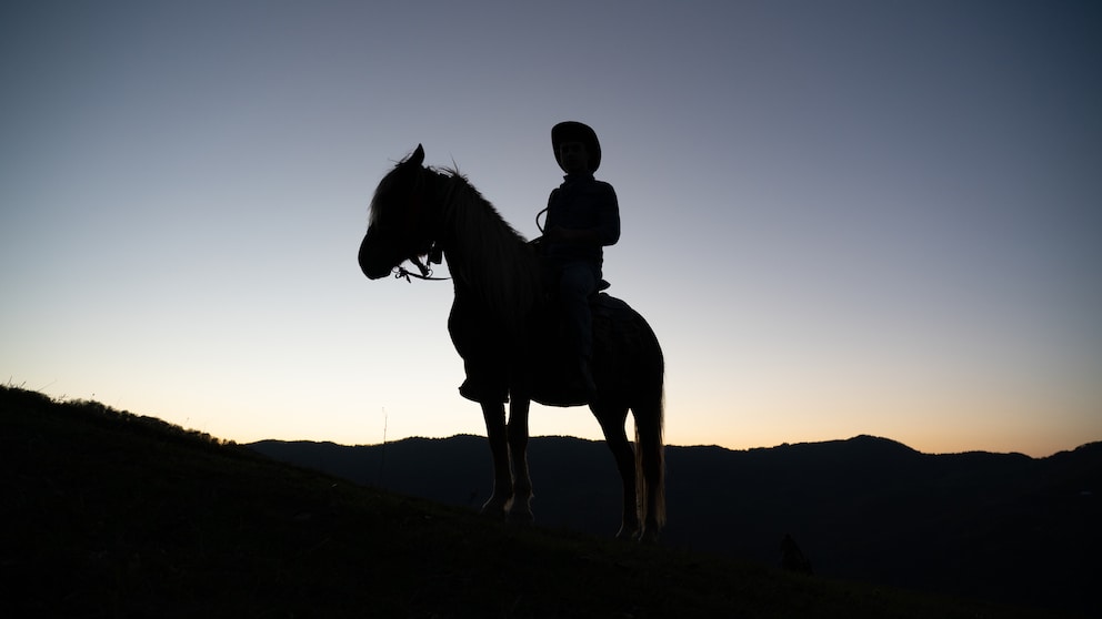 Dunkle Silhouette eines Cowboys auf Pferd vor Sonnenuntergang