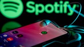 Symbolbild: Spotify-App auf Smartphone und im Hintergrund das Logo.