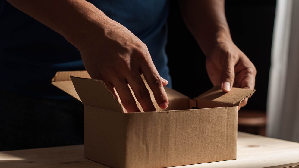 Männlich Hände greifen nach einem Postpaket.