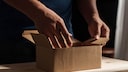 Männlich Hände greifen nach einem Postpaket.
