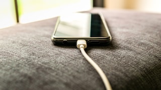Symbolbild für mAh/Milliamperestunden: Handy lädt mit Kabel auf