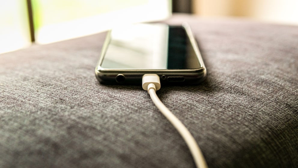 Symbolbild für mAh/Milliamperestunden: Handy lädt mit Kabel auf
