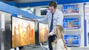 Fernseher kaufen im Laden: Frau mit TV-Verkäufer und Geräten