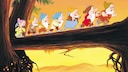 Ausschnitt aus dem Disney-Film „Schneewittchen und die sieben Zwerge“, das die Zwerge über eine Baumstamm-Brücke laufend zeigt.