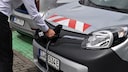 Mann lädt ein Auto mit E-Kennzeichen auf.