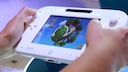 Zwei Hände halten eine weiße Wii U und spielen ein Game.