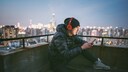 Man sitzt mit roten Kopfhörer und Smartphone