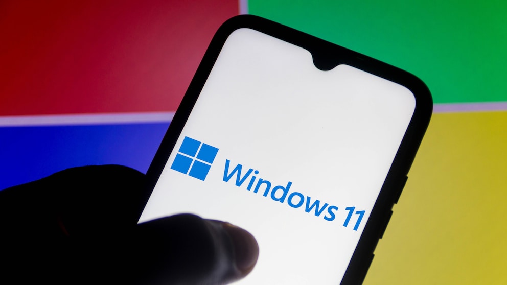 Windows 11 auf dem Smartphone mit Microsoft-Logo im Hintergrund