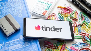 Tinder Logo auf einem Smartphone mit Bürosachen im Hintergrund