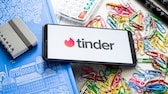 Tinder Logo auf einem Smartphone mit Bürosachen im Hintergrund