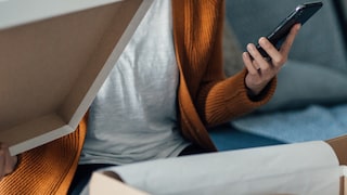 Amazon Prime Day 2023 Symbolbild Online Shopping: junge Frau mit Handy und Schuhkarton